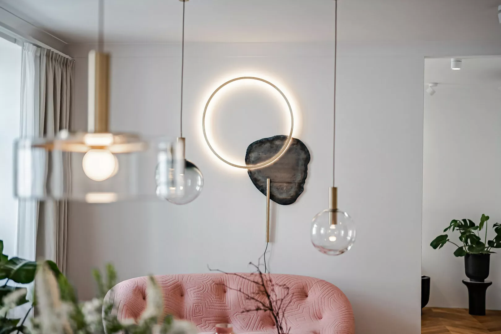 Modern living room with stylish lighting and pink sofa.